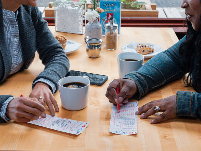 close up of two people filling out a Keno slip while drinking coffee