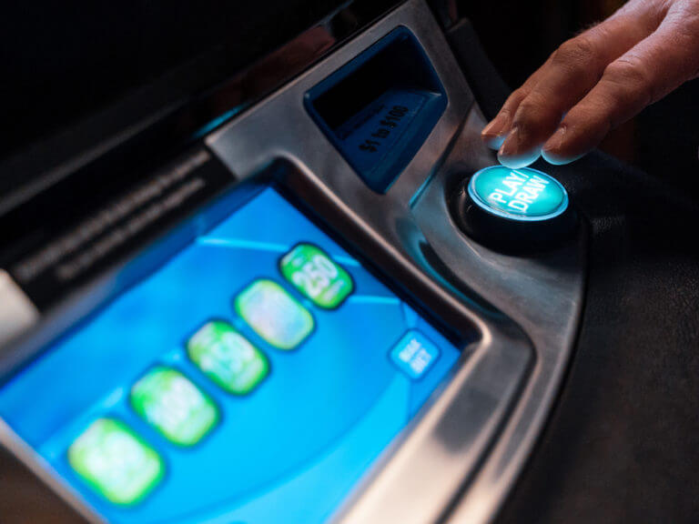 close up of video lottery machine with hand pressing play button