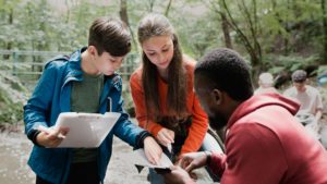 two students in state park setting, gathered around a teacher