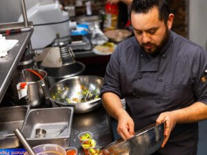 A chef stirring ingredients in a commercial kitchen